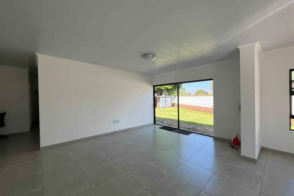 A bright, open-plan living area featuring neutral tiled flooring and a large sliding glass door providing direct access to the rear garden.