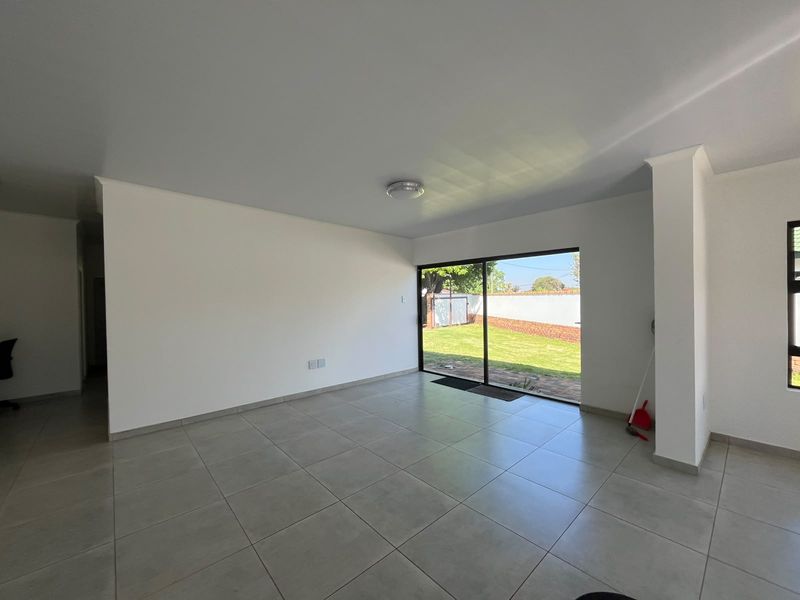 A bright, open-plan living area featuring neutral tiled flooring and a large sliding glass door providing direct access to the rear garden.