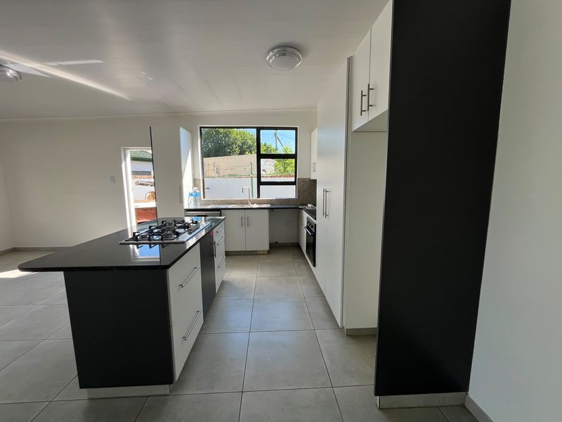 Modern kitchen featuring a central island with a gas hob, built-in oven, ample cabinetry, and tiled flooring in an open-plan layout.