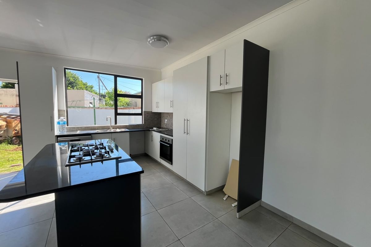 Modern kitchen featuring a central island with gas hob, built-in oven, ample cabinetry, and tiled flooring, offering a clean and functional workspace.