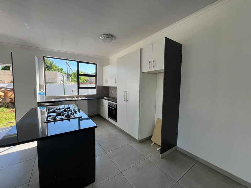 Modern kitchen featuring a central island with gas hob, built-in oven, ample cabinetry, and tiled flooring, offering a clean and functional workspace.