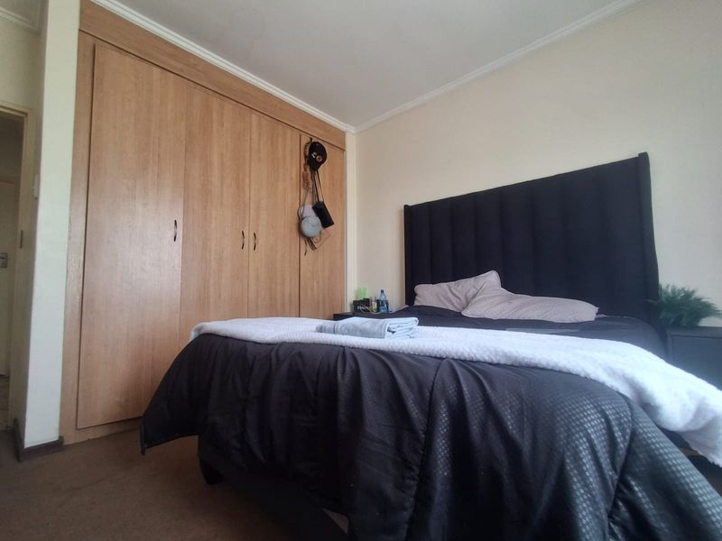 A bedroom featuring a large built-in wooden wardrobe and neutral wall finishes.