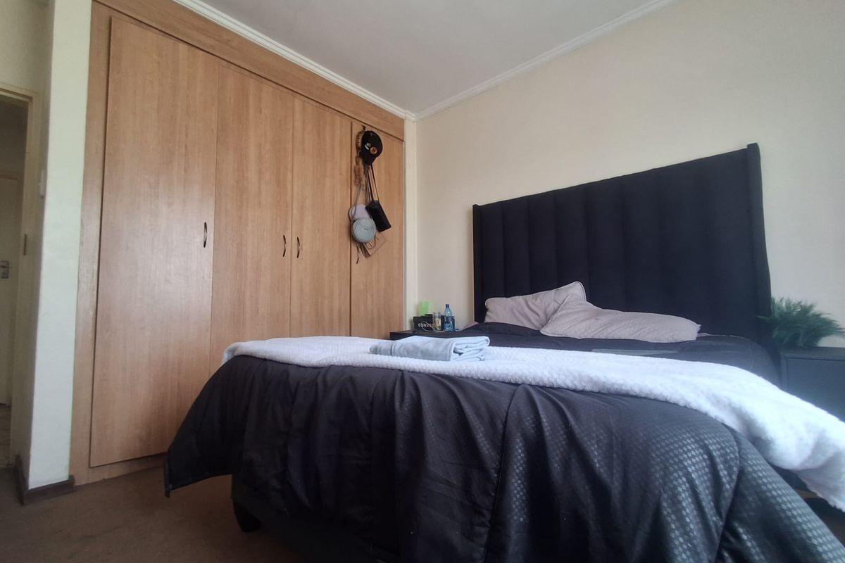 A bedroom featuring a large built-in wooden wardrobe and neutral wall finishes.