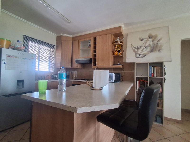 A functional kitchen featuring light wood-finish cabinetry, a central island with breakfast bar seating, and tiled flooring.