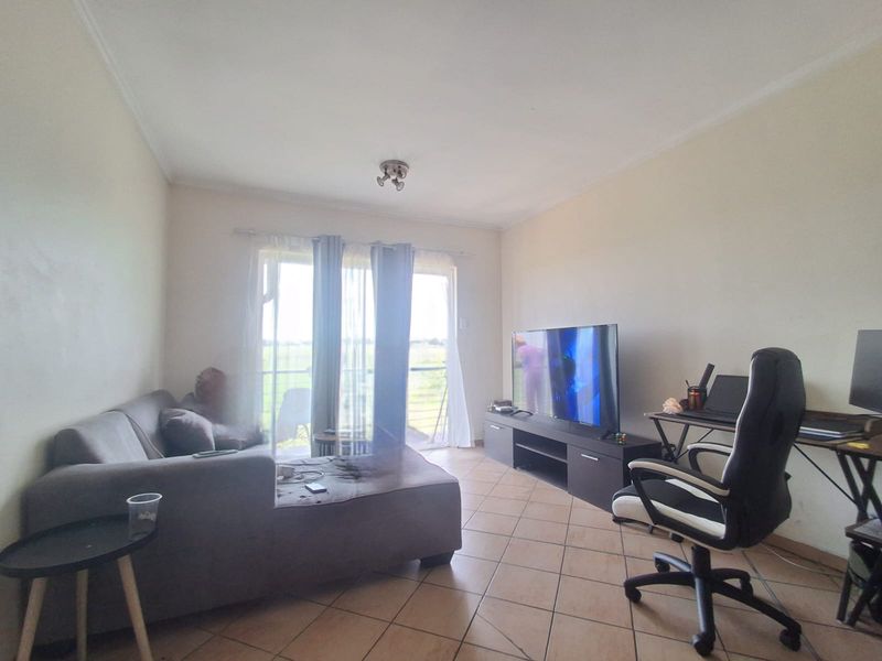 A living room featuring tiled flooring and a sliding glass door that provides access to an outdoor area.