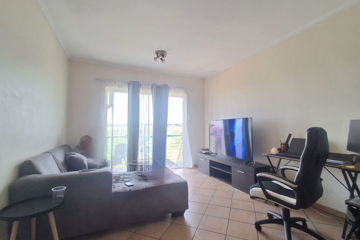 A living room featuring tiled flooring and a sliding glass door that provides access to an outdoor area.
