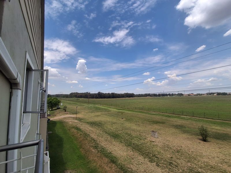 An elevated view from a balcony overlooking an expansive open field and natural landscape.