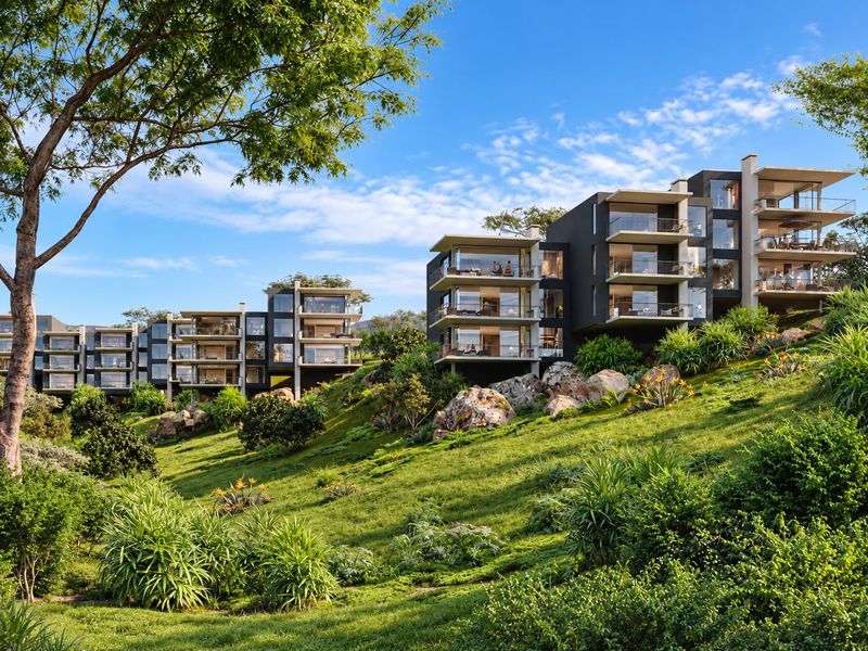A modern apartment complex featuring tiered balconies and expansive glass facades, set against a beautifully landscaped hillside.