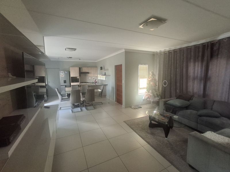 Spacious open-plan living and dining area featuring tiled floors and a modern kitchen with built-in cabinetry and integrated appliances.
