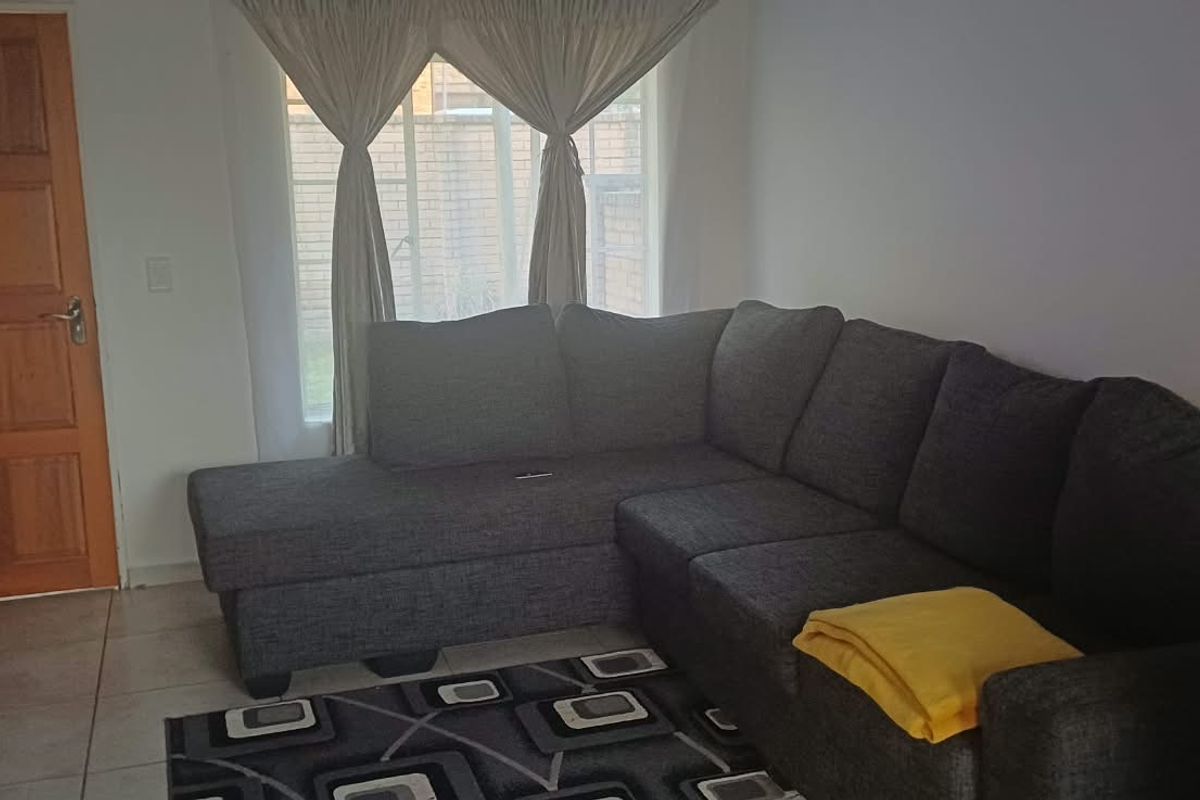 A comfortable living room featuring tiled flooring and a solid timber door, providing a functional and well-lit space for relaxation.