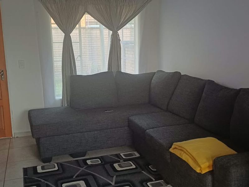 A comfortable living room featuring tiled flooring and a solid timber door, providing a functional and well-lit space for relaxation.