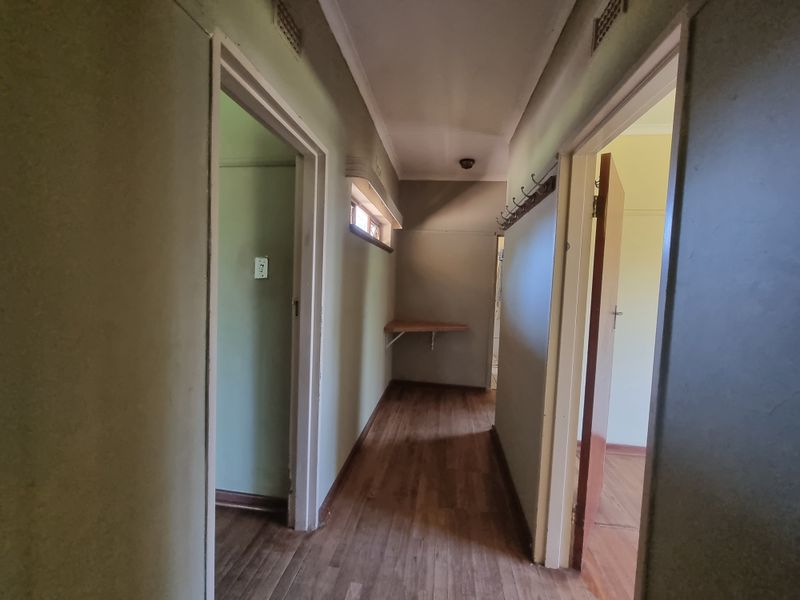 A functional hallway featuring laminate flooring, a built-in wall shelf, and access to multiple rooms, presenting a blank canvas for interior updates.