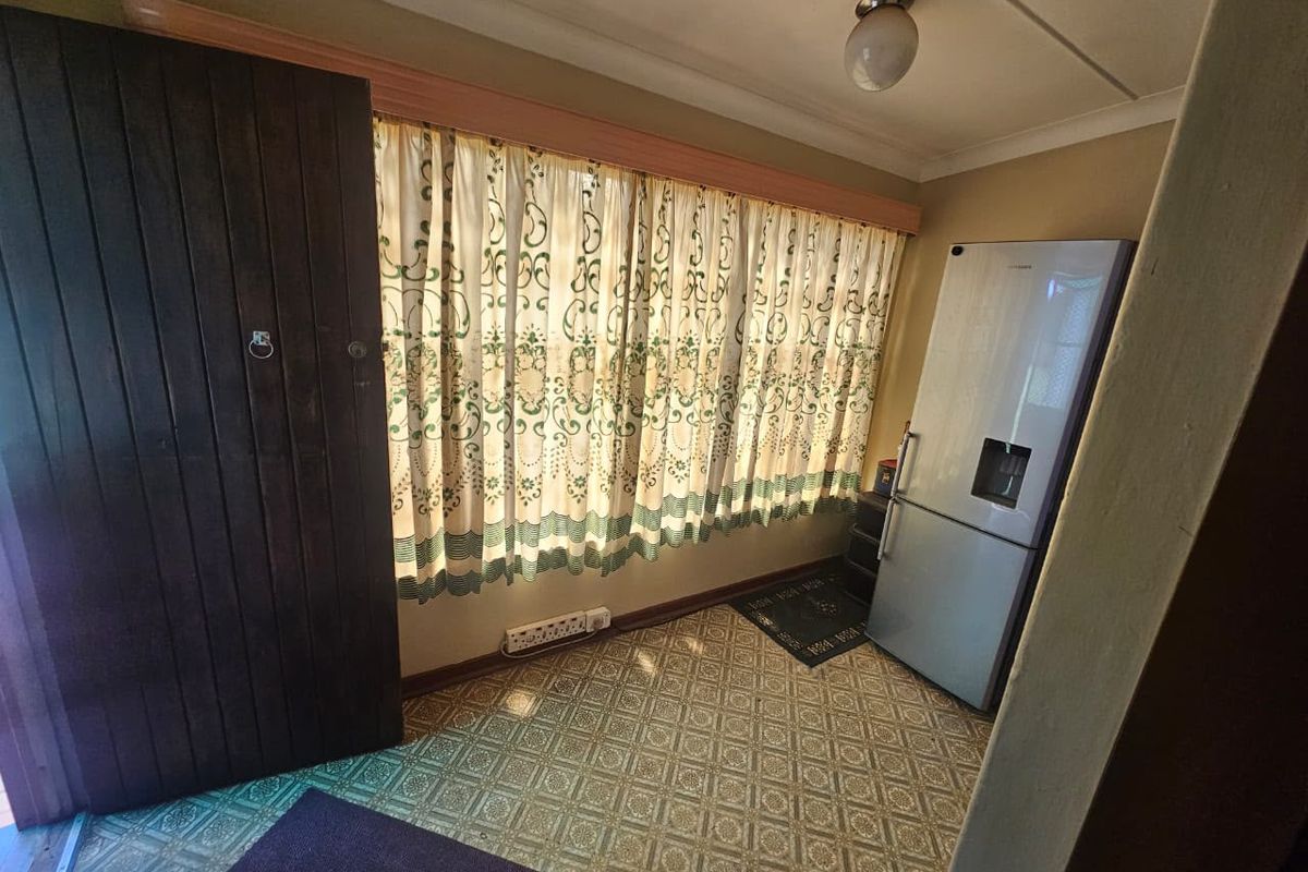 A simple, functional living space featuring patterned vinyl flooring, a ceiling light fixture, and a wooden door.