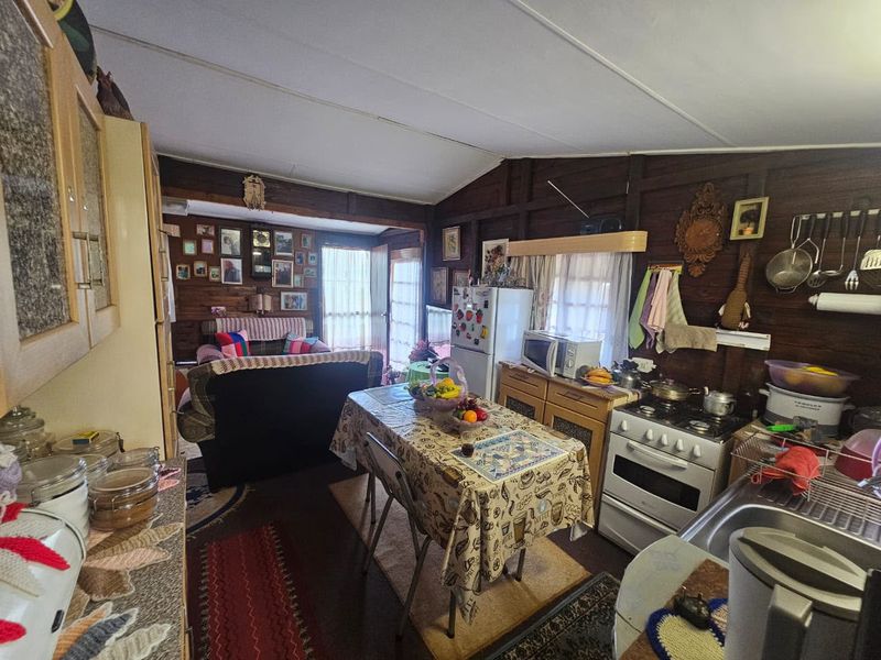 Open-plan kitchen and living area featuring timber wall paneling, functional cabinetry, and a gas stove, offering a rustic, lived-in aesthetic.