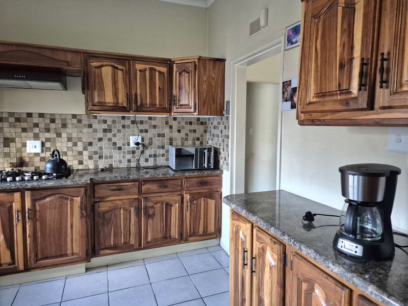 A functional kitchen featuring warm-toned wooden cabinetry, granite countertops, and a mosaic tile backsplash, providing ample storage and workspace.