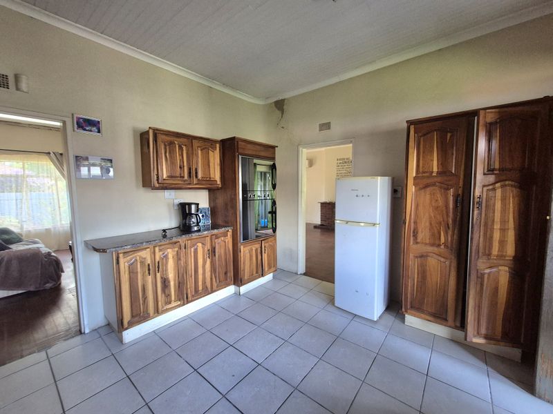 A dated kitchen featuring traditional wooden cabinetry, built-in oven, and tiled flooring, requiring cosmetic updates to modernize the space.