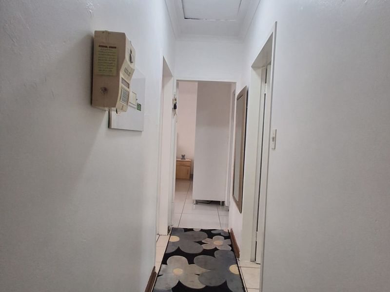 A functional interior hallway featuring tiled flooring, a ceiling access hatch, and a wall-mounted intercom system.