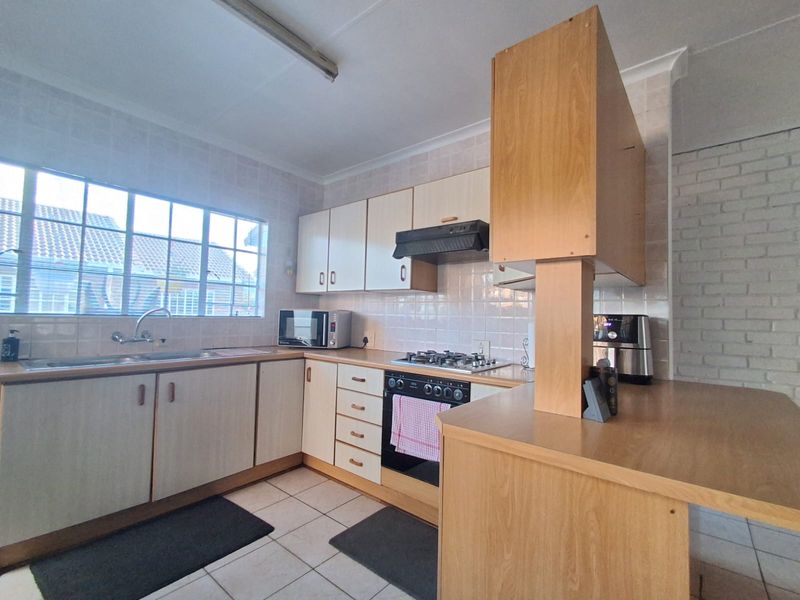 Functional kitchen featuring built-in cabinetry, gas hob, oven, extractor fan, and tiled finishes, offering a practical layout with potential for modern updates.