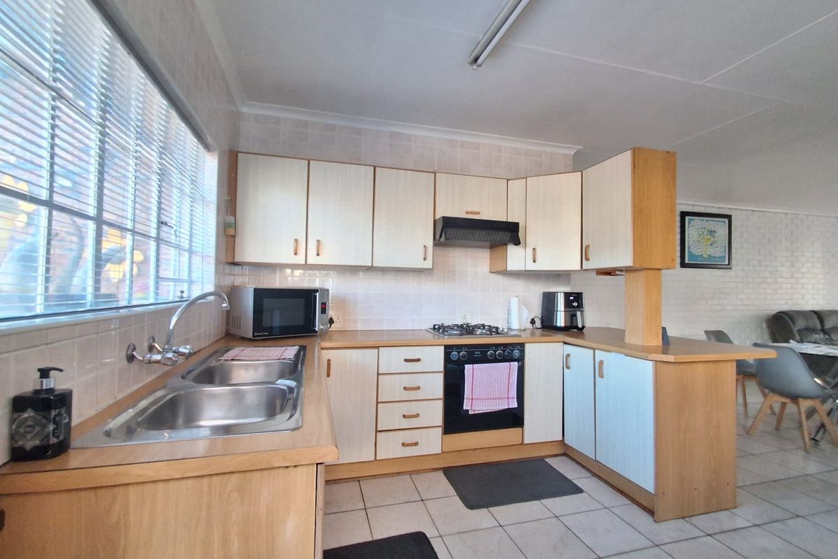 Functional kitchen featuring laminate cabinetry, built-in oven with gas hob, extractor fan, and double bowl stainless steel sink with tiled backsplash.