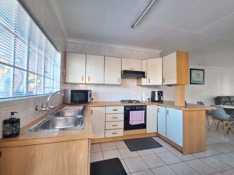 Functional kitchen featuring laminate cabinetry, built-in oven with gas hob, extractor fan, and double bowl stainless steel sink with tiled backsplash.