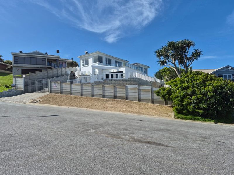 A street-level view of the property featuring a multi-level facade, retaining walls, and a paved driveway entrance.
