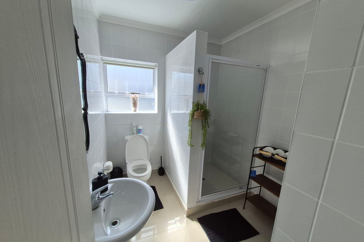 A clean and functional bathroom featuring a pedestal basin, toilet, and a separate shower enclosure with tiled finishes throughout.