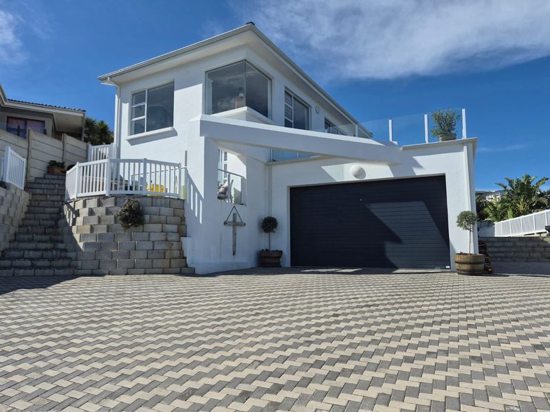 Modern two-story home exterior featuring a paved driveway, integrated garage, and elevated balcony with glass balustrades.