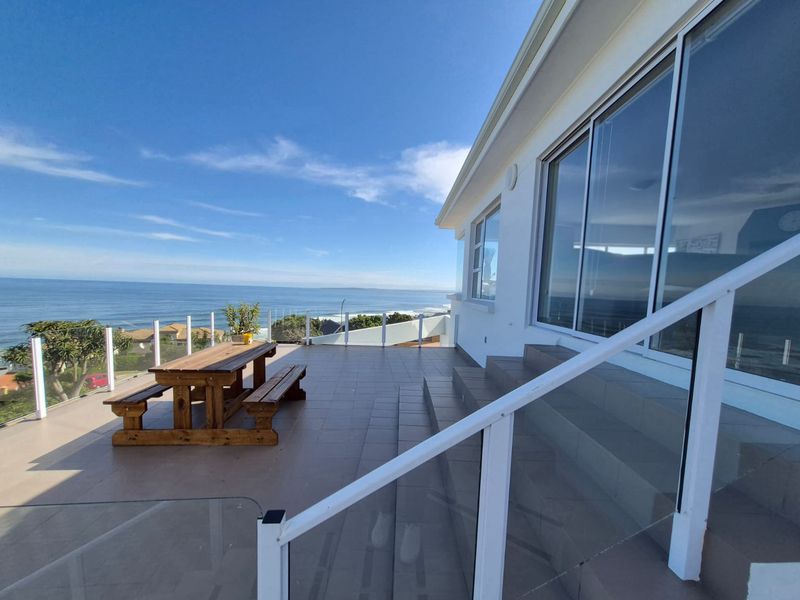 Spacious outdoor balcony featuring tiled flooring, a modern glass balustrade, and large sliding glass doors with panoramic ocean views.