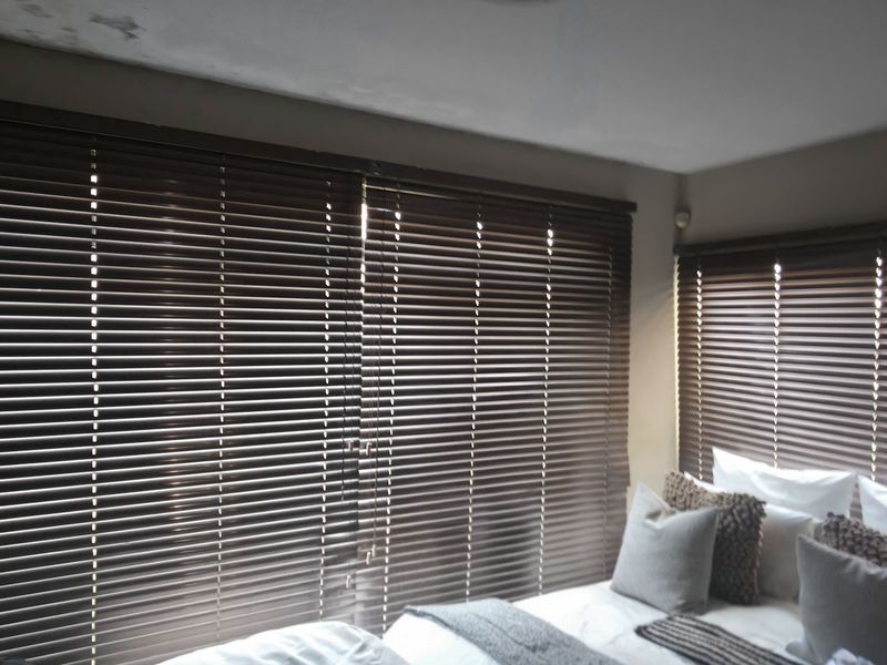 A bedroom featuring dark venetian blinds and visible water staining on the ceiling, indicating potential maintenance requirements.