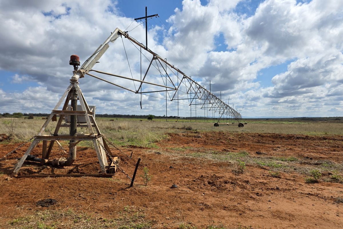 A large-scale center pivot irrigation system situated on open farmland, showing signs of age and maintenance requirements.