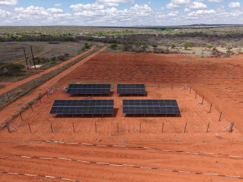 Aerial view of a farm property featuring a ground-mounted solar panel array within a fenced enclosure and extensive irrigation infrastructure.