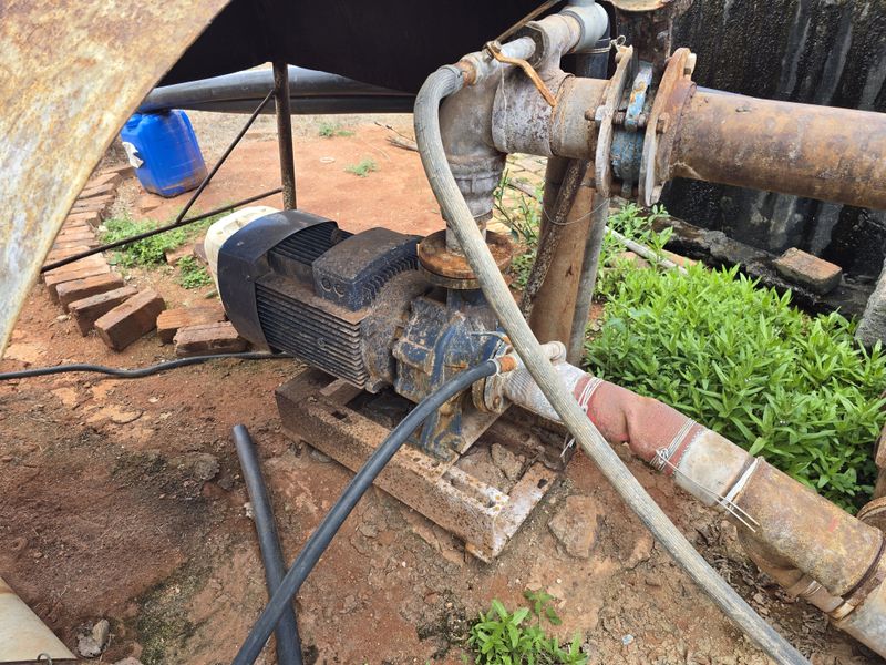 Outdoor water pump and irrigation piping infrastructure showing significant signs of age and corrosion.
