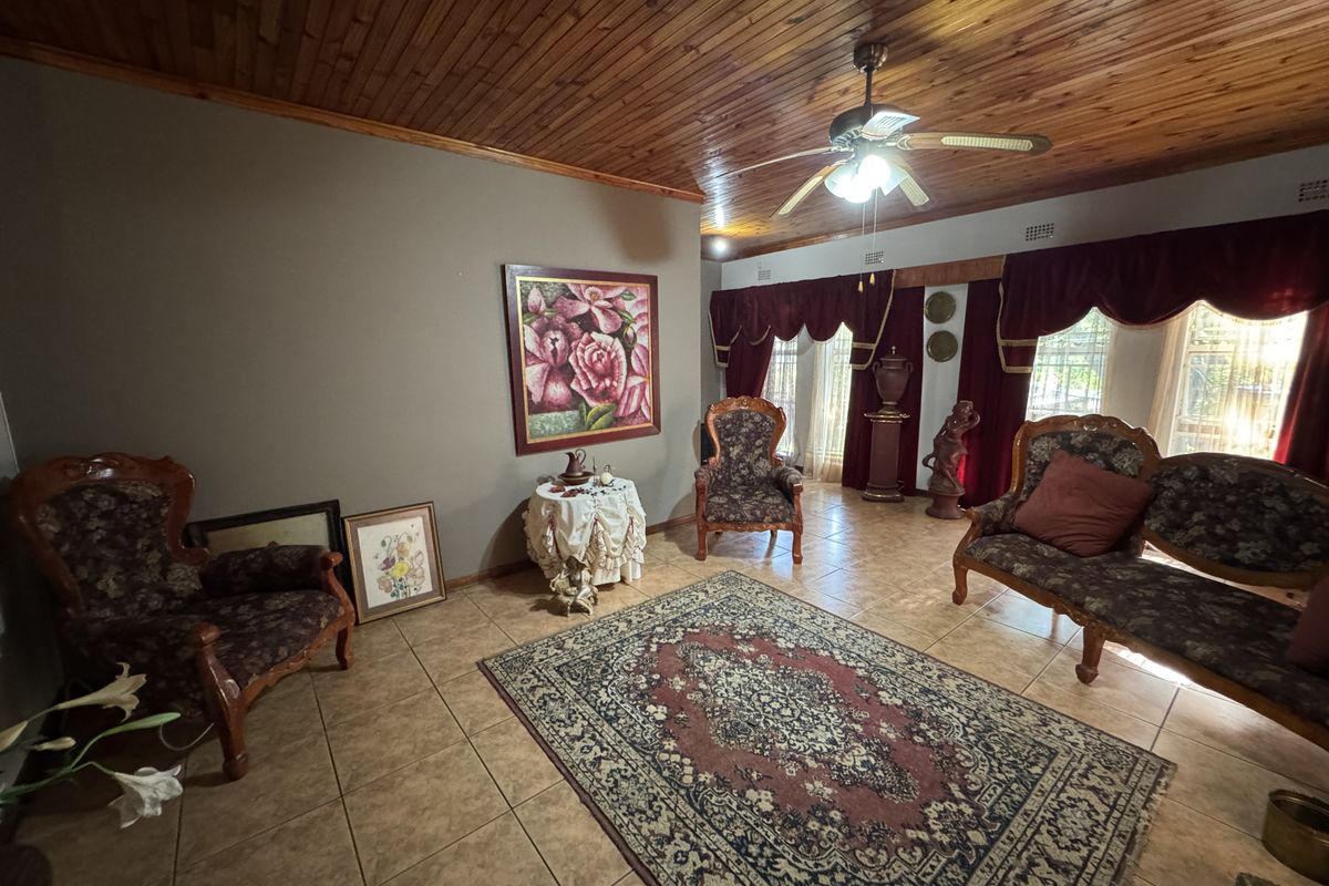 A living room featuring a timber tongue and groove ceiling, ceiling fan, and ceramic floor tiles, offering a traditional aesthetic.