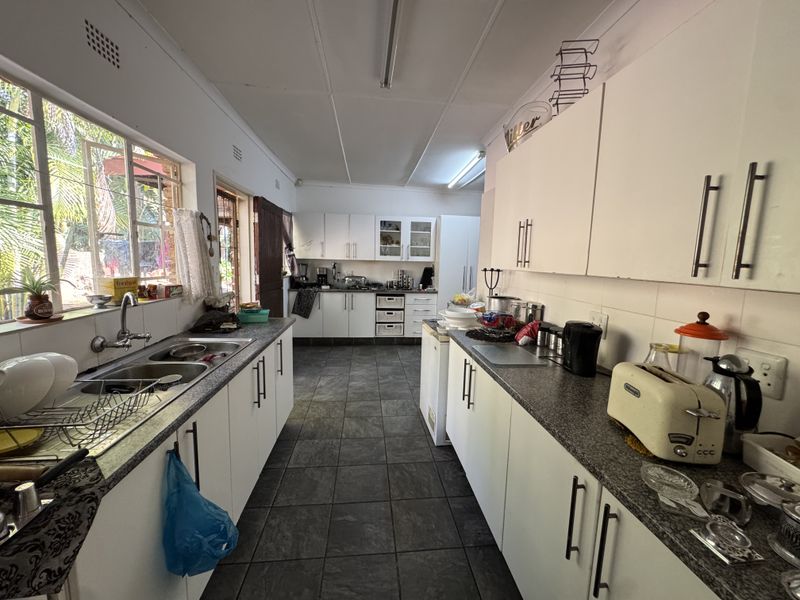 A functional galley-style kitchen featuring granite countertops, double basin sink, and ample built-in cabinetry with tiled flooring throughout.