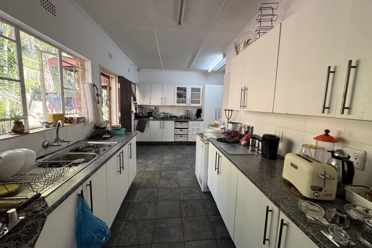 A functional galley-style kitchen featuring granite countertops, double basin sink, and ample built-in cabinetry with tiled flooring throughout.