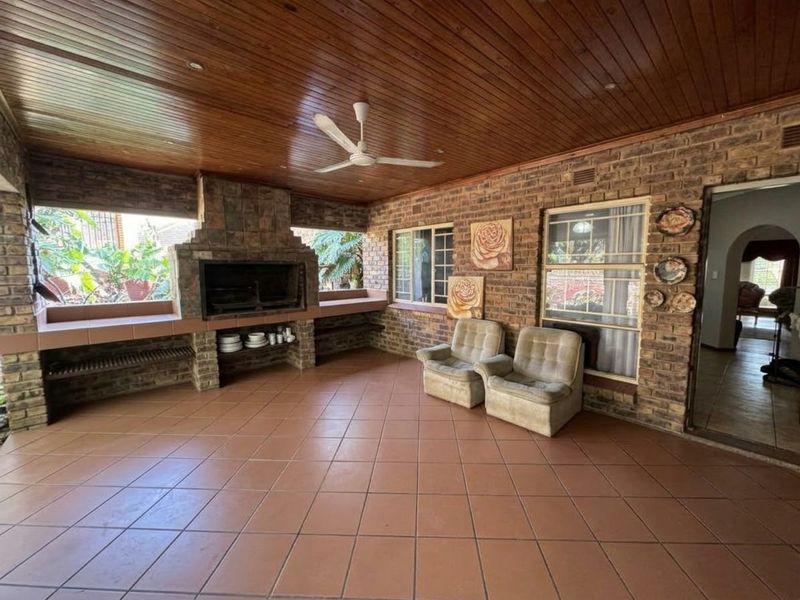 Spacious covered patio featuring a built-in braai, exposed brick walls, and a timber ceiling, offering a functional outdoor entertainment area.