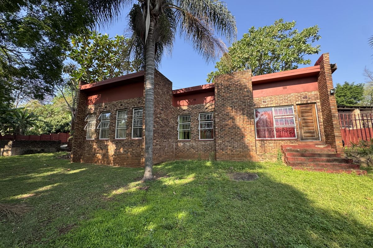 Rear view of a face brick house featuring casement windows, a timber entrance door, and concrete steps leading to the garden.