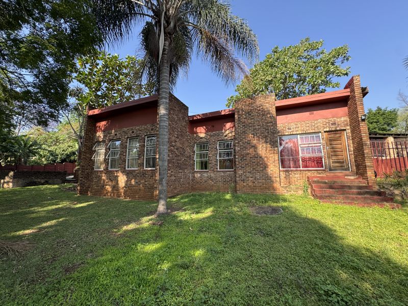 Rear view of a face brick house featuring casement windows, a timber entrance door, and concrete steps leading to the garden.