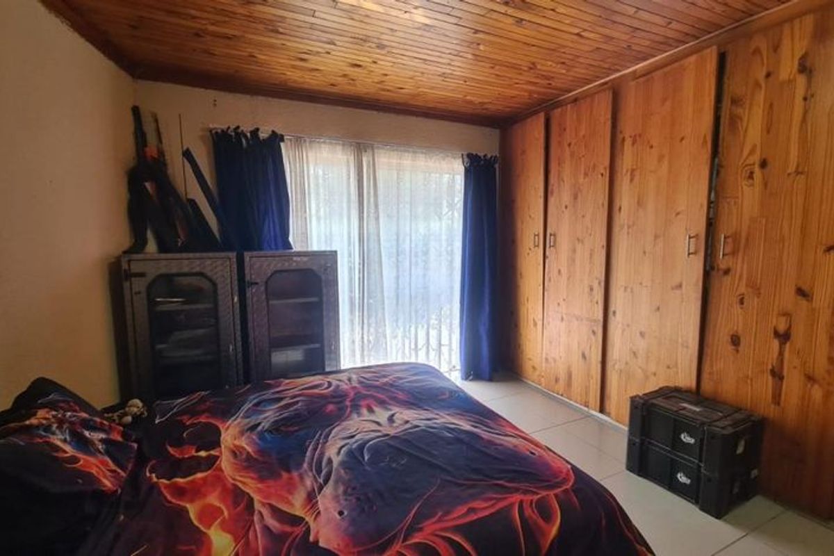 A bedroom featuring built-in wooden cupboards, a wooden ceiling, and tiled flooring with access to an outdoor area via a sliding glass door.