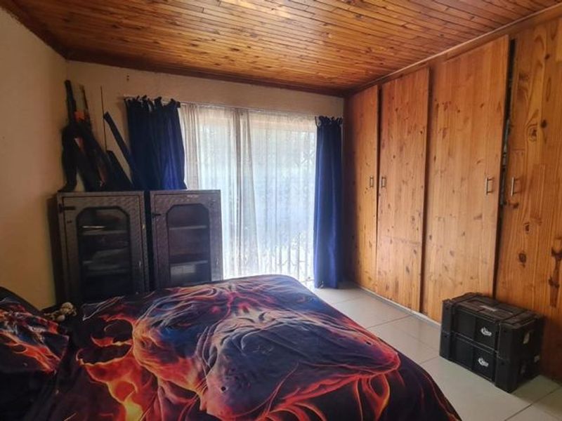 A bedroom featuring built-in wooden cupboards, a wooden ceiling, and tiled flooring with access to an outdoor area via a sliding glass door.