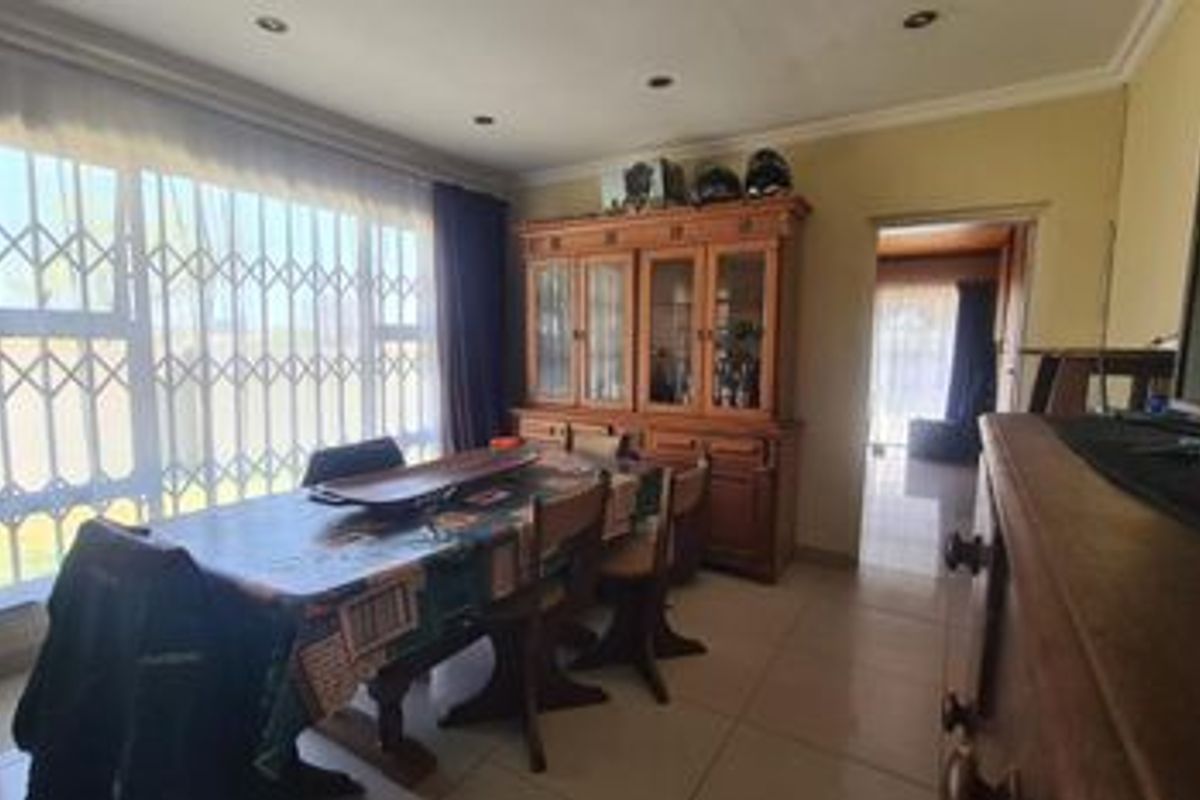 A dining room featuring tiled flooring, recessed downlighting, and a large window fitted with a security gate.