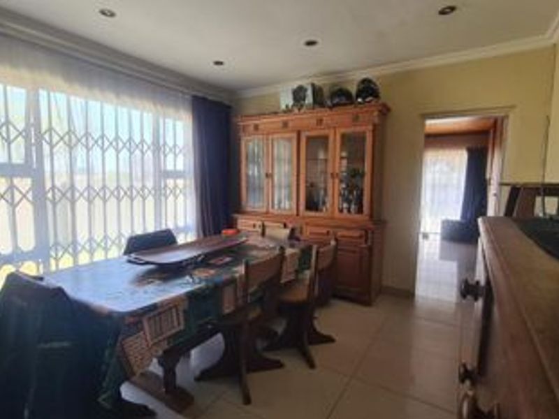 A dining room featuring tiled flooring, recessed downlighting, and a large window fitted with a security gate.