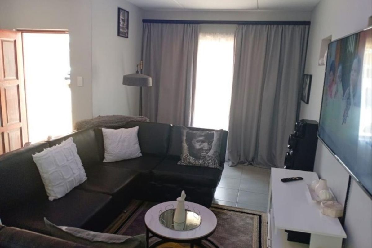 A comfortable living room featuring tiled flooring and large window curtains, providing a functional and inviting space for relaxation.