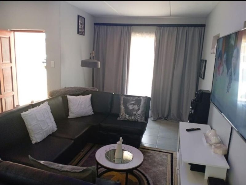A comfortable living room featuring tiled flooring and large window curtains, providing a functional and inviting space for relaxation.