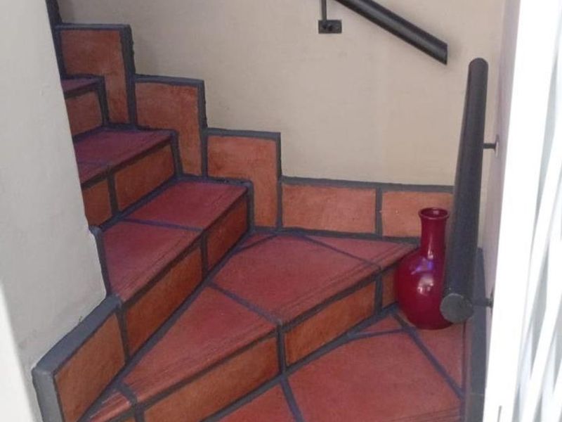 A staircase featuring terracotta-style tiled steps and a dark metal handrail, providing access between levels.