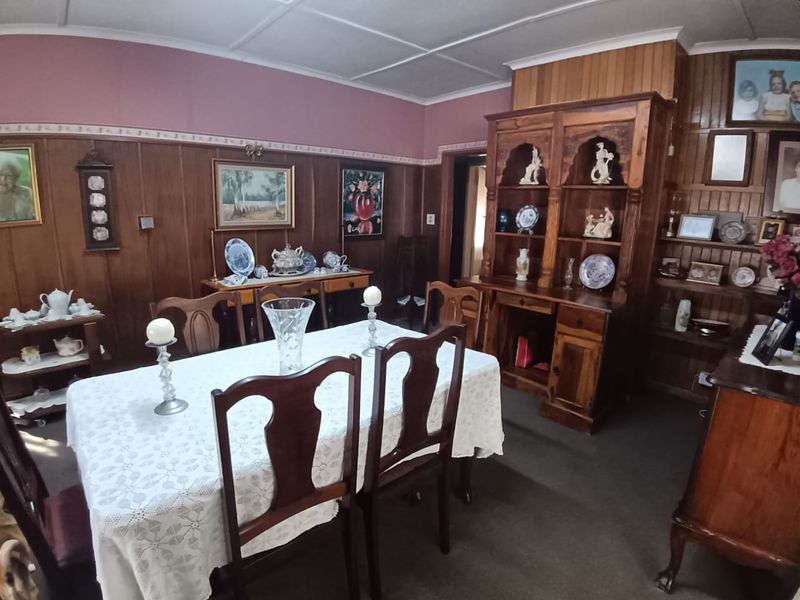 A traditional dining room featuring extensive timber wall paneling, built-in wooden cabinetry, and a coved ceiling, offering a classic and warm aesthetic.