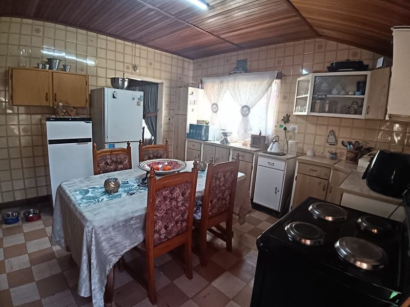 A dated kitchen featuring tiled walls, timber ceiling, and built-in cabinetry, offering potential for a modern renovation to update the space.