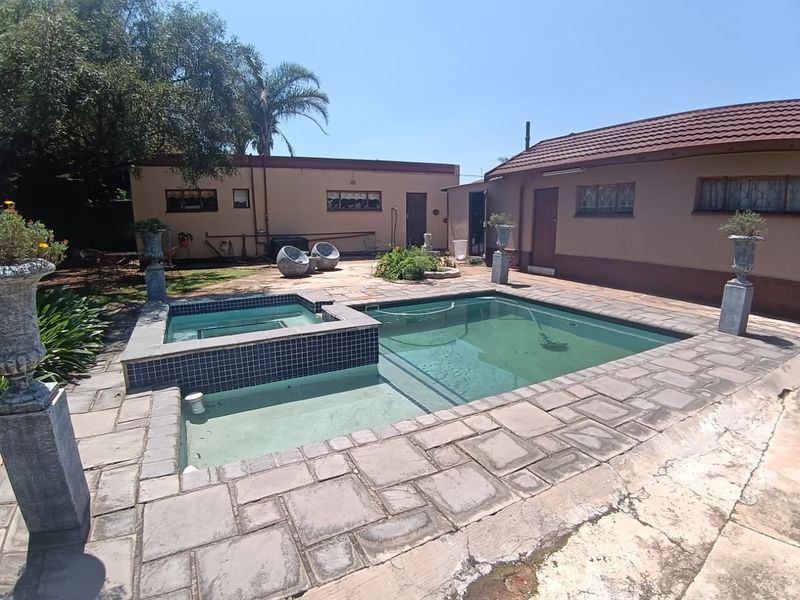 Outdoor pool area featuring an integrated spa and paved surround, set within a private rear garden space.