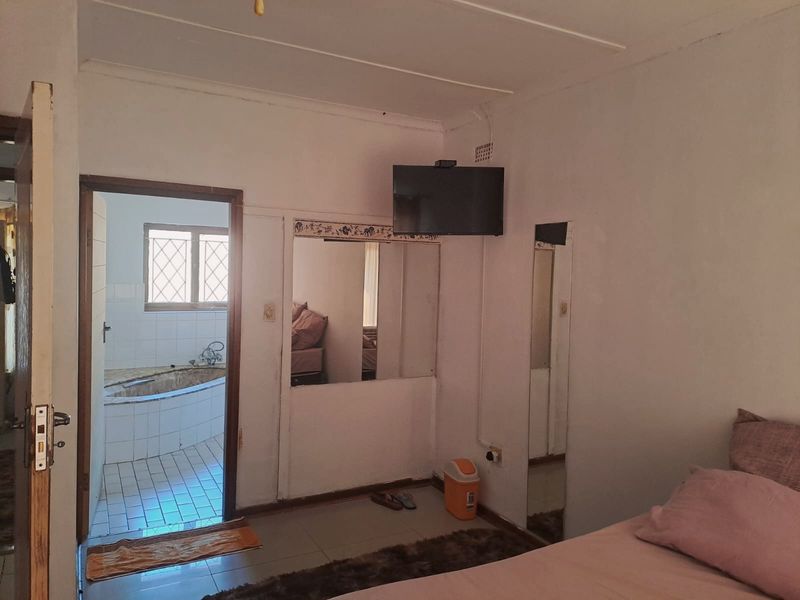 Bedroom featuring tiled flooring, a built-in mirror, and direct access to an en-suite bathroom with a corner bathtub.