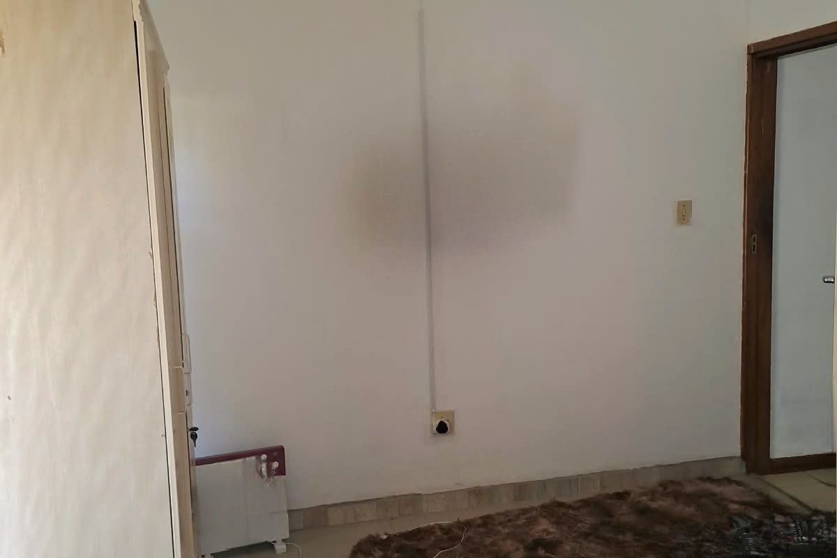 A bedroom featuring tiled flooring and visible wall staining, requiring cosmetic updates to improve the overall aesthetic and condition.